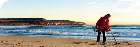 Picture of person using gold detector on beach