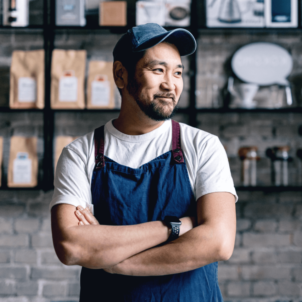 Man in cap and blue apron in cafe