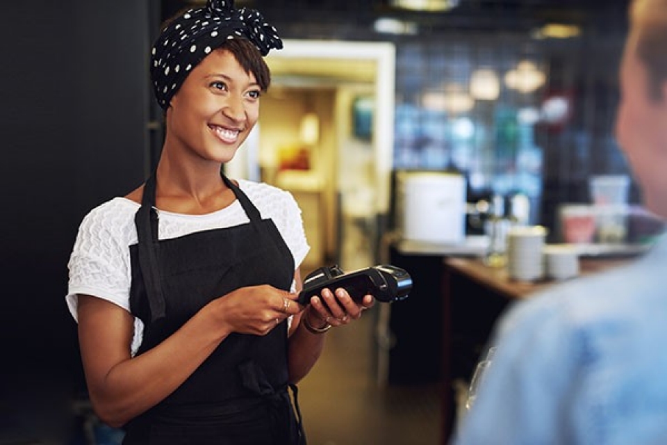 Women in apron and headscarf taking payment on EFTPOS machine